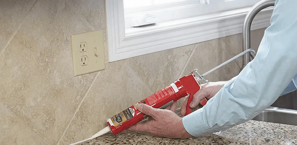 Handyman applying caulk along a kitchen backsplash and countertop seam in Lakeland, FL